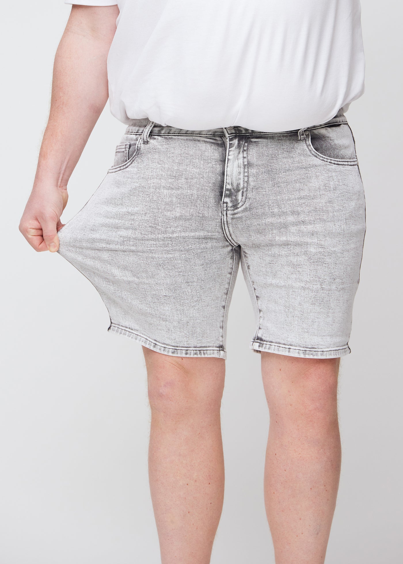 Plus-size model strækker shortsene ved låret for at vise stretch.