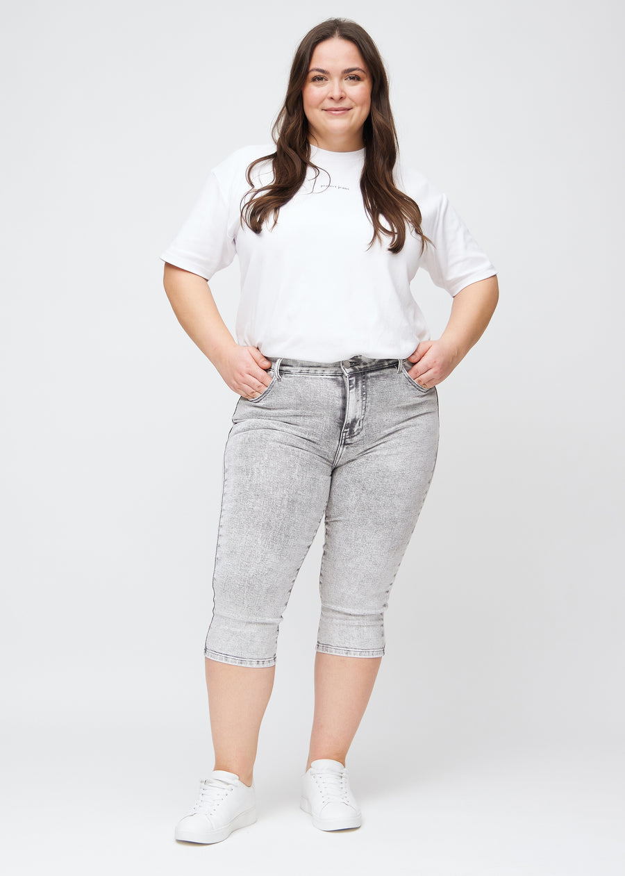 Fuldt billede af en plus-size model i lysegrå denim skinny capris.