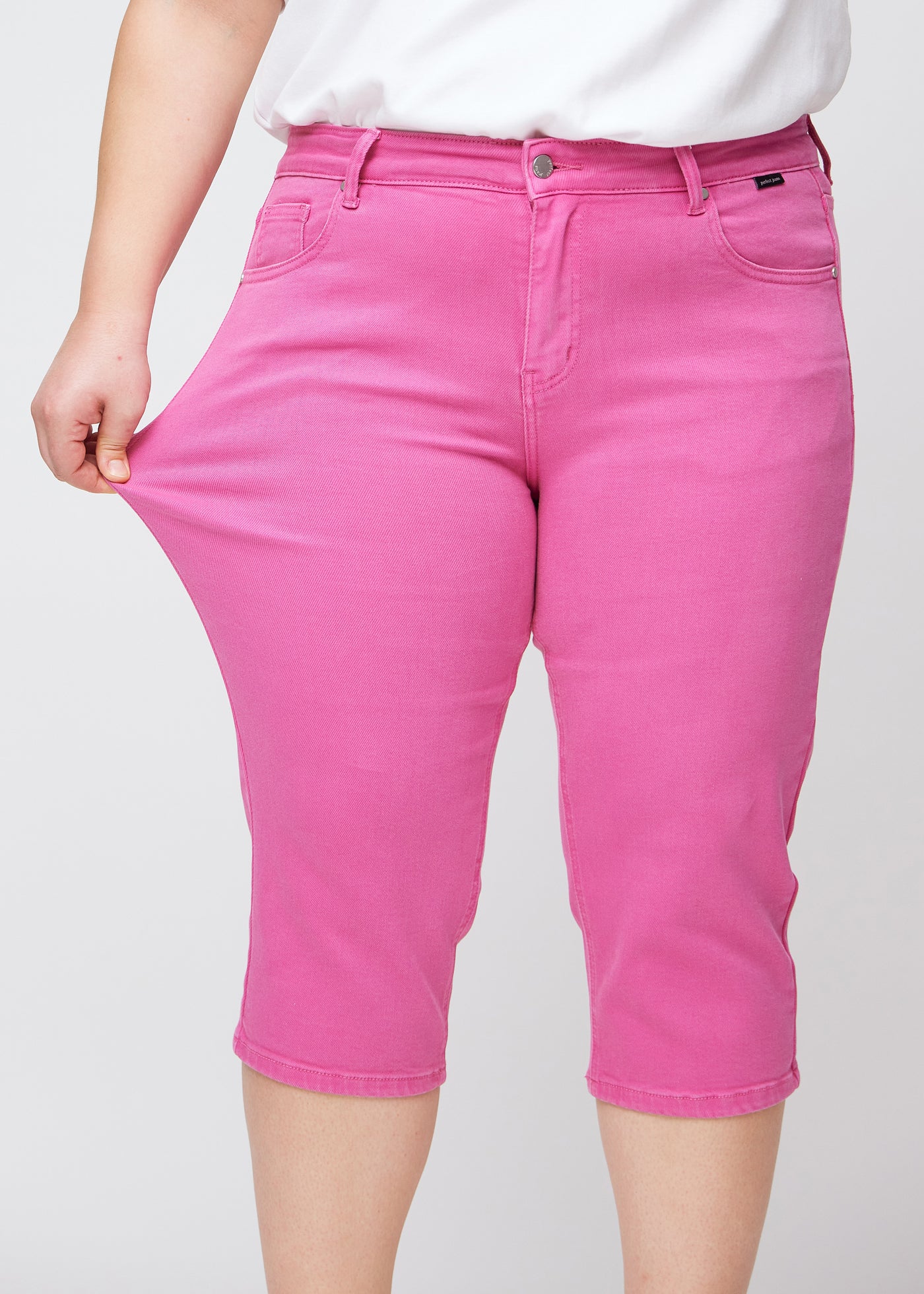 Plus-size model viser stretch ved at trække i caprisene ved låret – fokus på komfort og fleksibilitet.