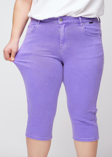 Plus-size model viser stretch ved at trække i caprisene ved låret – fokus på komfort og fleksibilitet.