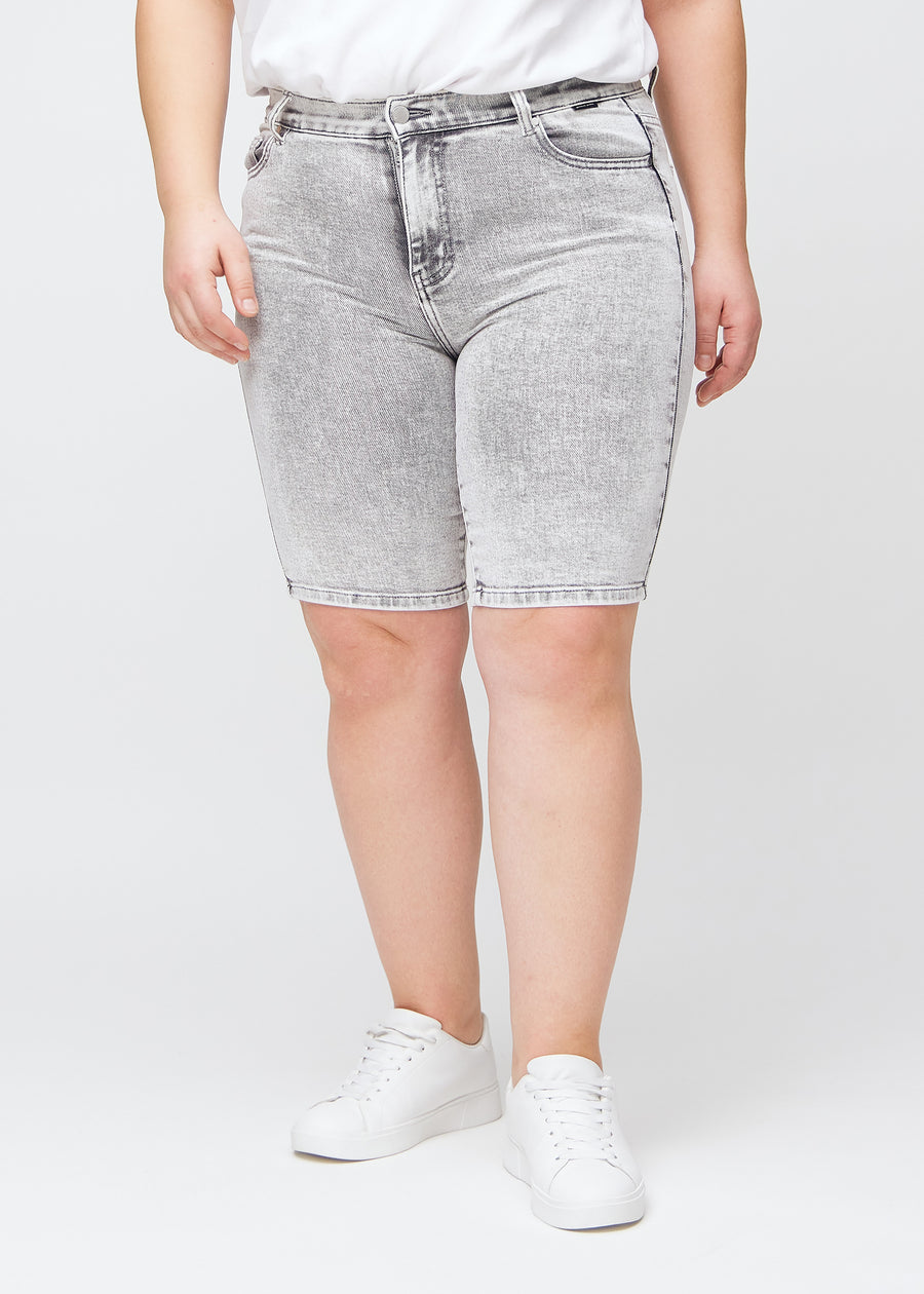 Lysegrå denim skinny middle shorts, modelnavn Ashes, som sidder tæt til låret og slutter lige over knæet på en plus-size model, set forfra.