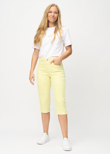 Fuldt billede af model i lysegule skinny capris.
