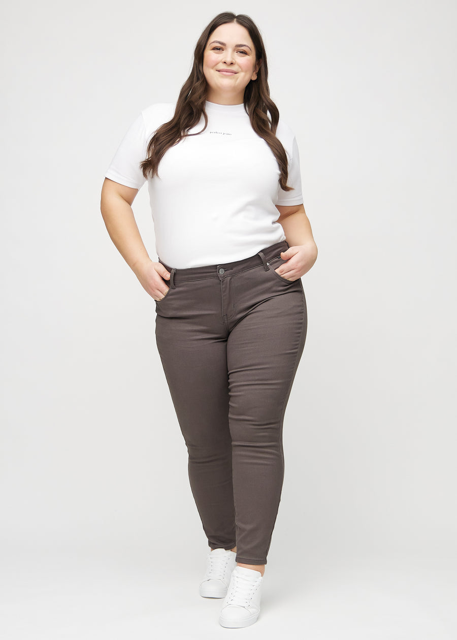 Fuldt billede af en plus-size model i gråbrune skinny jeans.