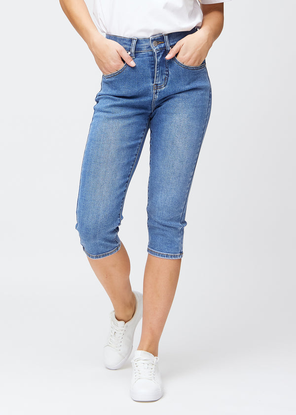 Blå denim slim capris, farve Rivers, med tætsiddende pasform der former benene og slutter lige under knæet – set forfra.