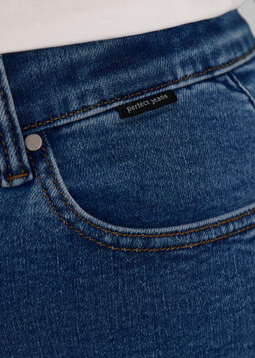 Nærbillede af mørkeblå denim med Perfect Jeans logoetiket ved forlommekanten, på en plus-size model.