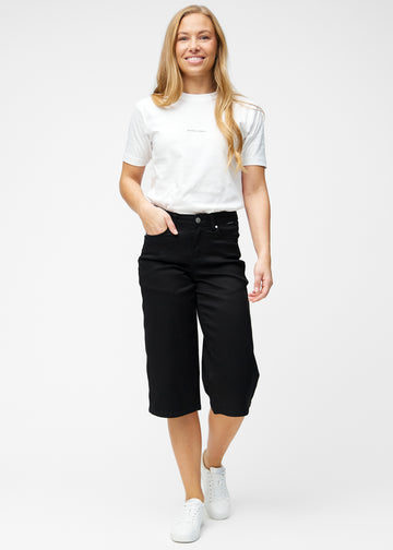 Fuldt billede af model i løse, sorte capris i farven Ravens, der går til lige under knæet.