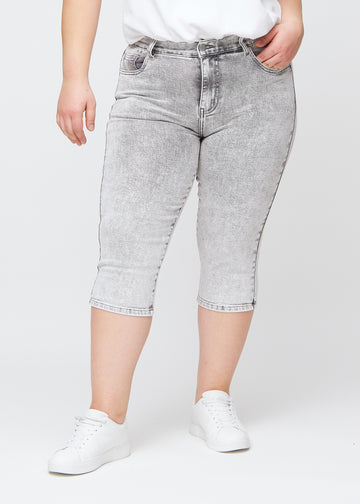 Lysegrå denim slim capris, farve Ashes, med tætsiddende pasform og længde lige under knæet – set forfra på plus-size model.