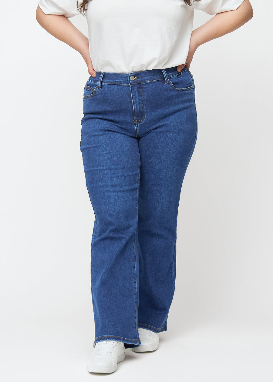 Dark blue mid-rise bootcut jeans in Oceans. Front view on a plus-size model, fitted through the hips and thighs with a gentle flare at the hem.