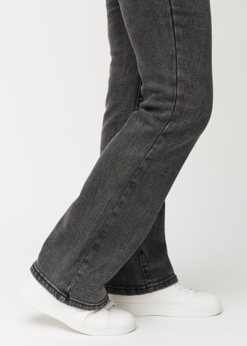 Dark grey mid-rise bootcut jeans in Shadows. Close-up of the ankle area on a model, showing the subtle bootcut flare.