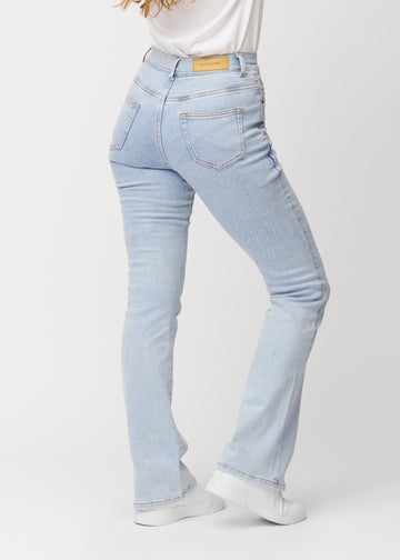Light blue mid-rise bootcut jeans in Waves. Back view on a model, showing the full fit.