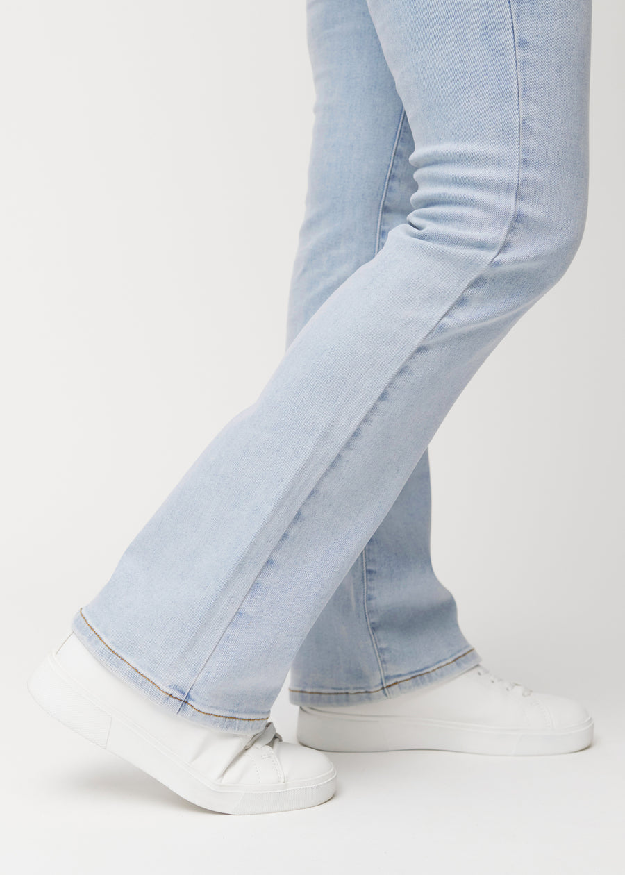 Light blue mid-rise bootcut jeans in Waves. Close-up of the ankle area on a model, showing the subtle bootcut flare.