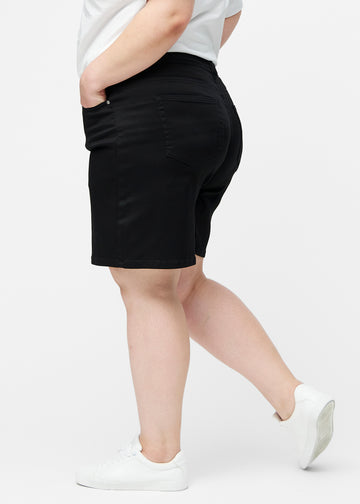 Løse, sorte shorts i farven Ravens set fra siden på plus-size model, hvor den brede pasform og længden til lige over knæet er synlig.