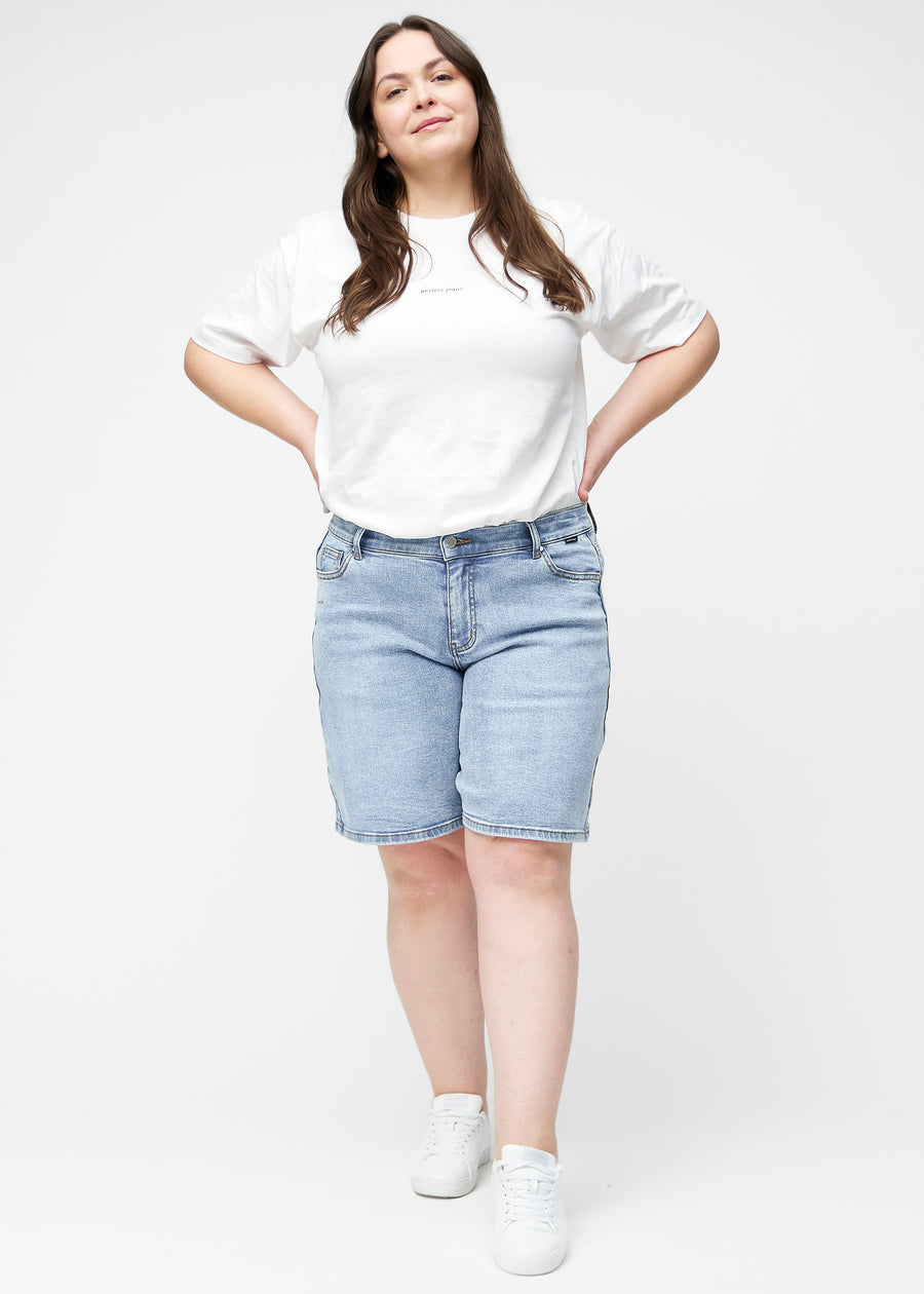 Full image of a plus-size model wearing loose, light blue denim shorts in the colour Waves, reaching just above the knee.