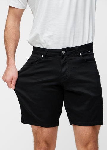 Model stretches the black shorts for men in the colour Ravens at the thigh to show the stretch of the material.