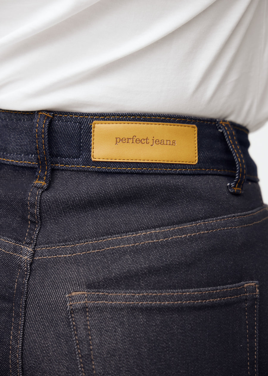 Close-up of deep dark blue denim with Perfect Jeans leather patch at the back waist.