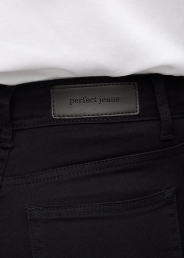 Close-up of black jeans material with the Perfect Jeans leather patch at the back of the waistband.