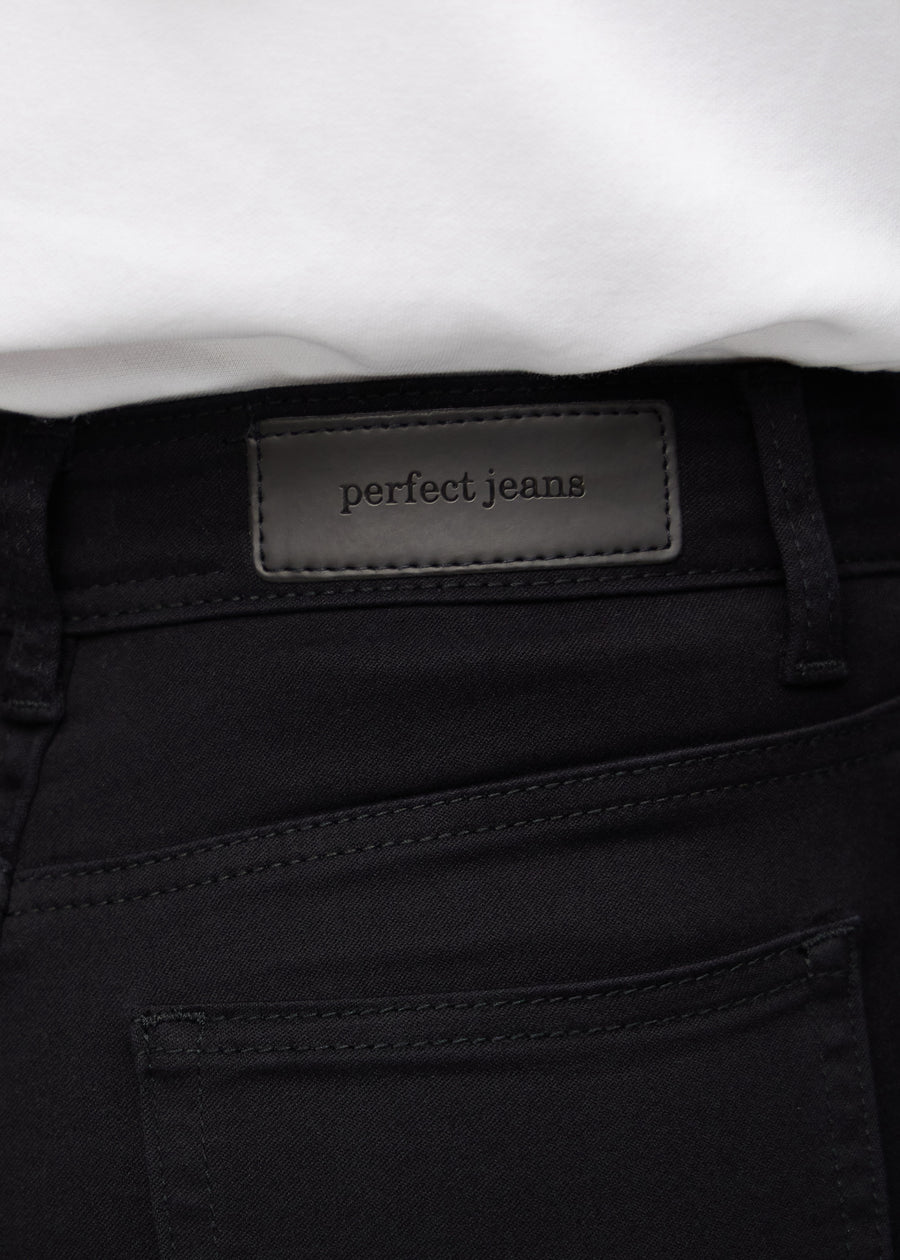 Close-up of black jeans material with the Perfect Jeans leather patch at the back of the waistband.