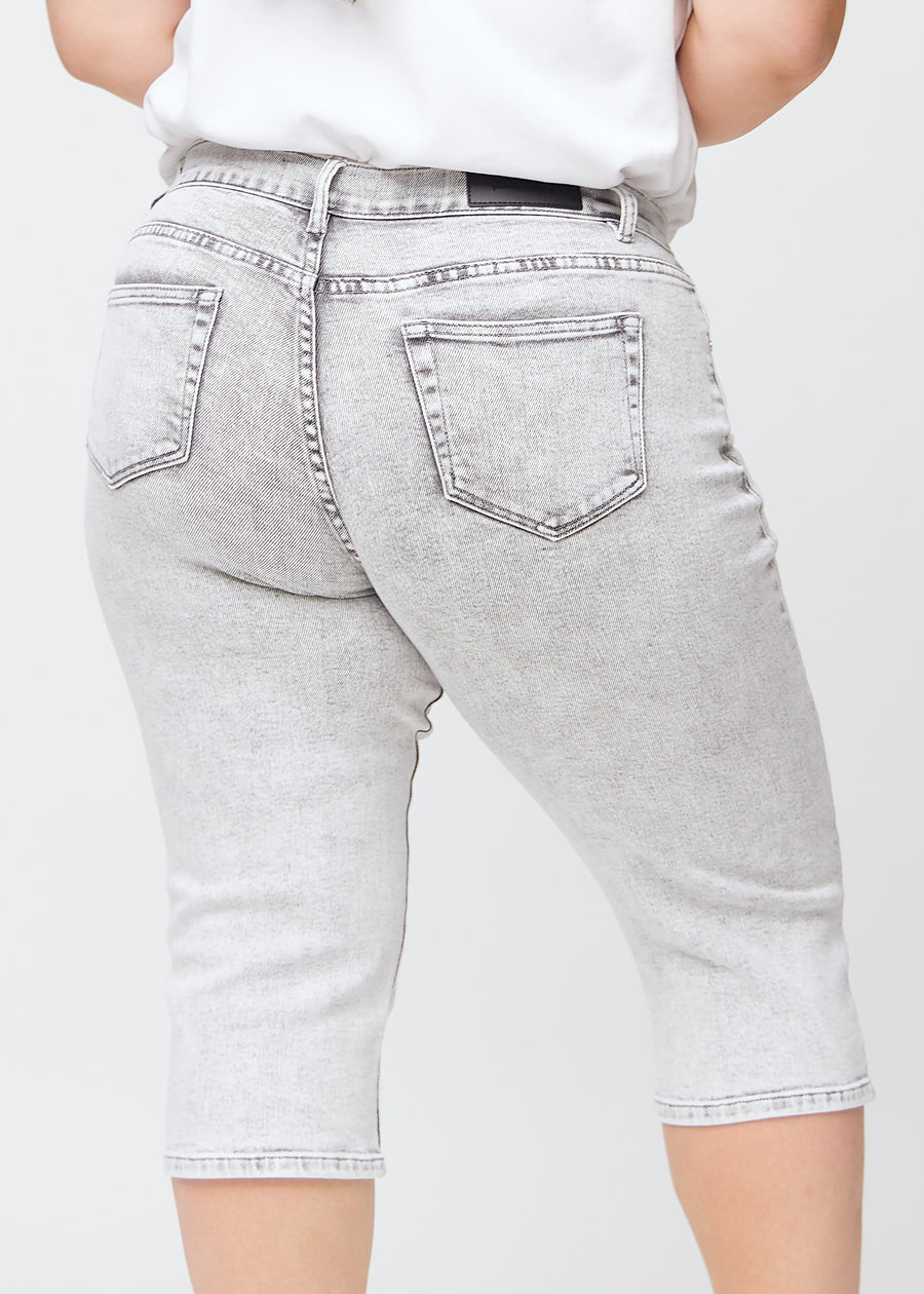 Light grey denim regular capris seen from the back up close on a plus-size model to show details.