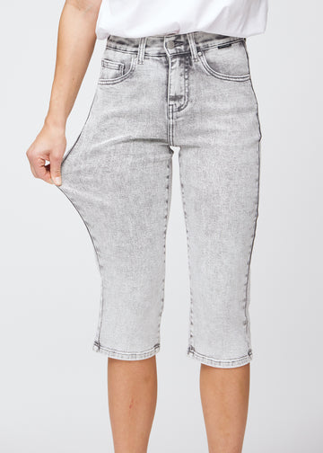 The model stretches the capris at the thigh to show the stretch.