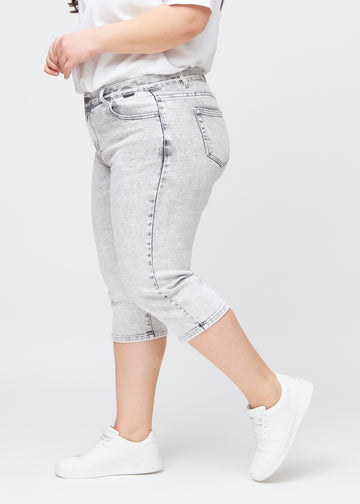 Light grey denim regular capris seen from the side on a plus-size model.
