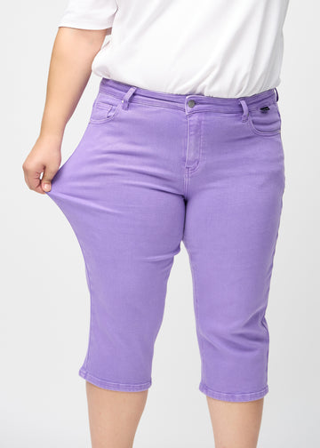 Plus-size model stretches the capris at the thigh to show the stretch.