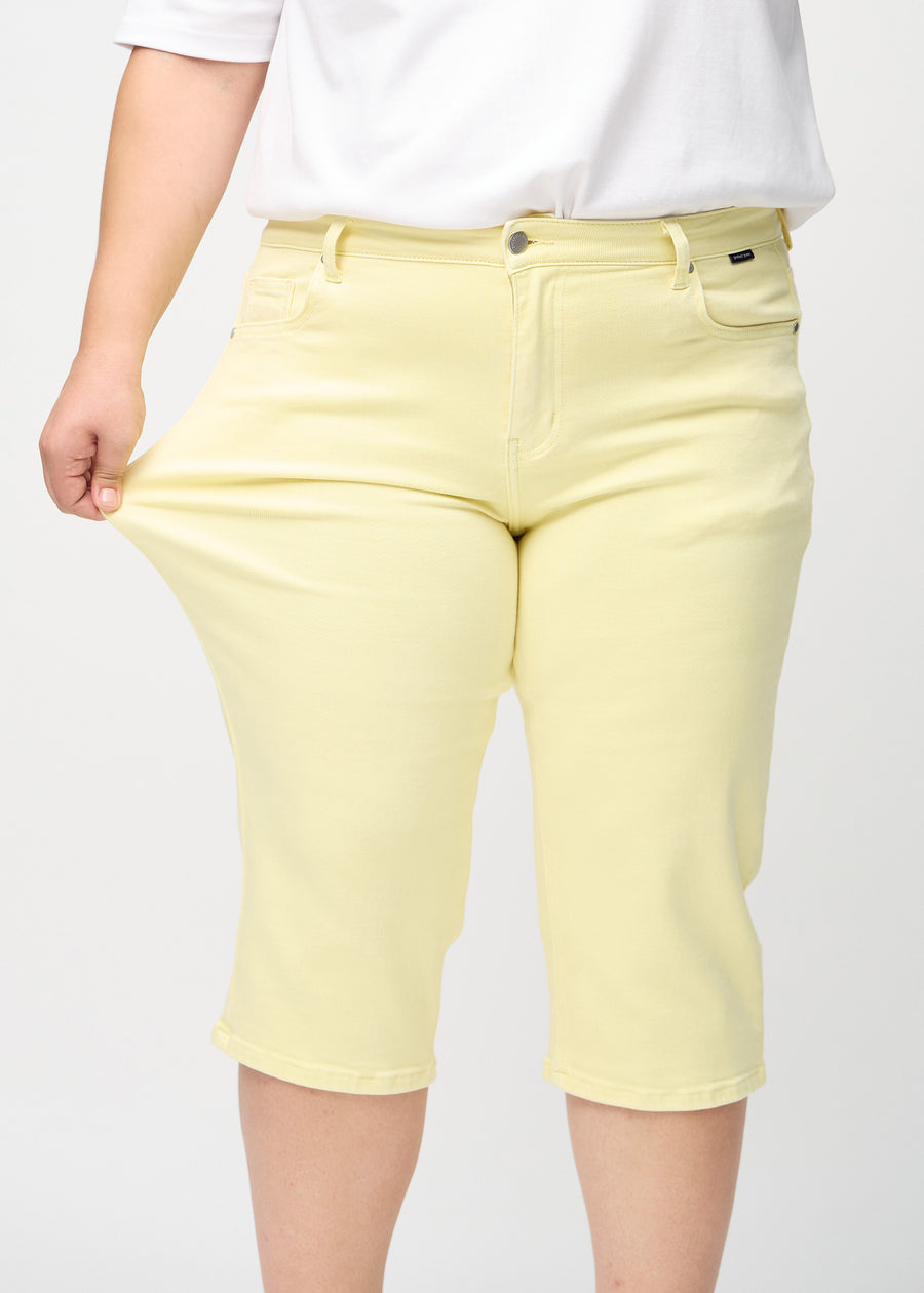 Plus-size model stretches the capris at the thigh to show the stretch.