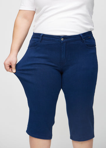 The plus-size model stretches the capris at the thigh to show the stretch.