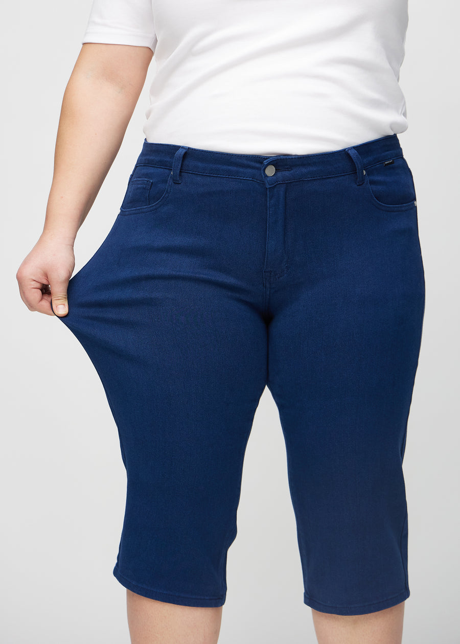 The plus-size model stretches the capris at the thigh to show the stretch.