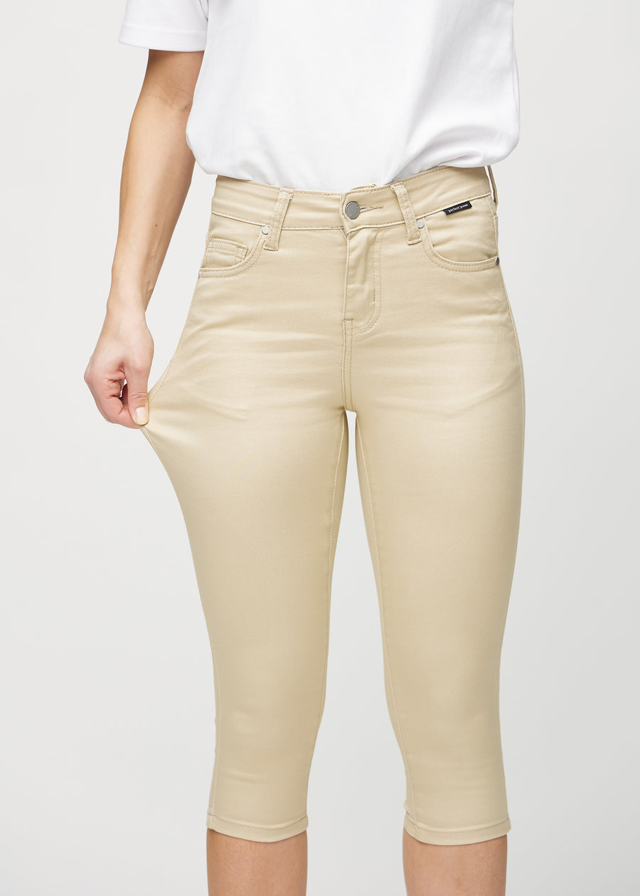 Skinny capris for women in beige fabric, color Gazelles. A model stretches the fabric to demonstrate its flexibility.