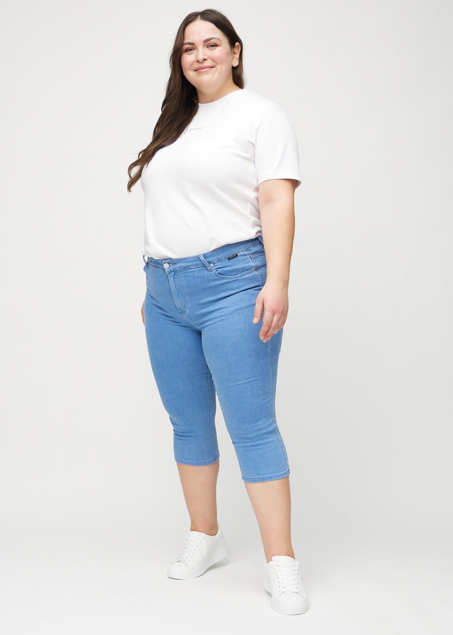Skinny capris for women in blue fabric, color Geraniums. Full-length view of a plus-size model wearing the capris.