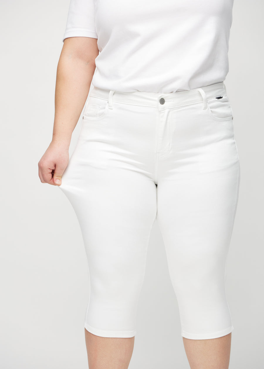 Skinny capris for women in white fabric, color Marguerites. A plus-size model stretches the fabric to demonstrate its flexibility.