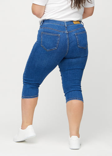 Skinny capris for women in dark blue denim, color Oceans. Back view on a plus-size model, showing the fit and back pockets.