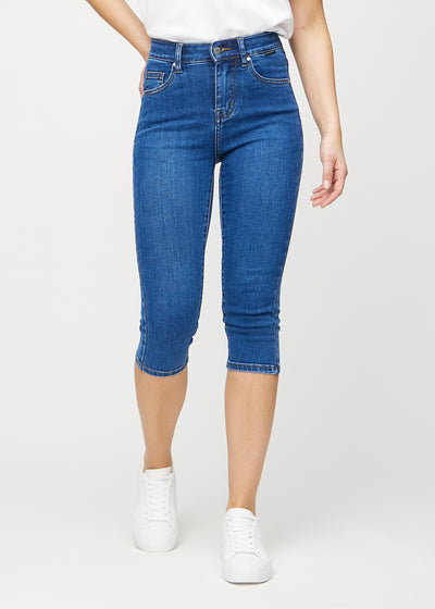 Skinny capris for women in dark blue denim, color Oceans. Front view on a model, showing the close-fitting legs ending just below the knee.
