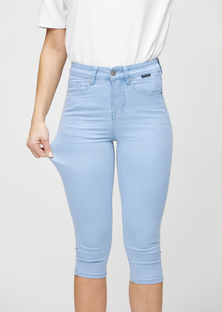 Skinny capris for women in light blue fabric, color Skies. A model stretches the fabric to demonstrate its flexibility.
