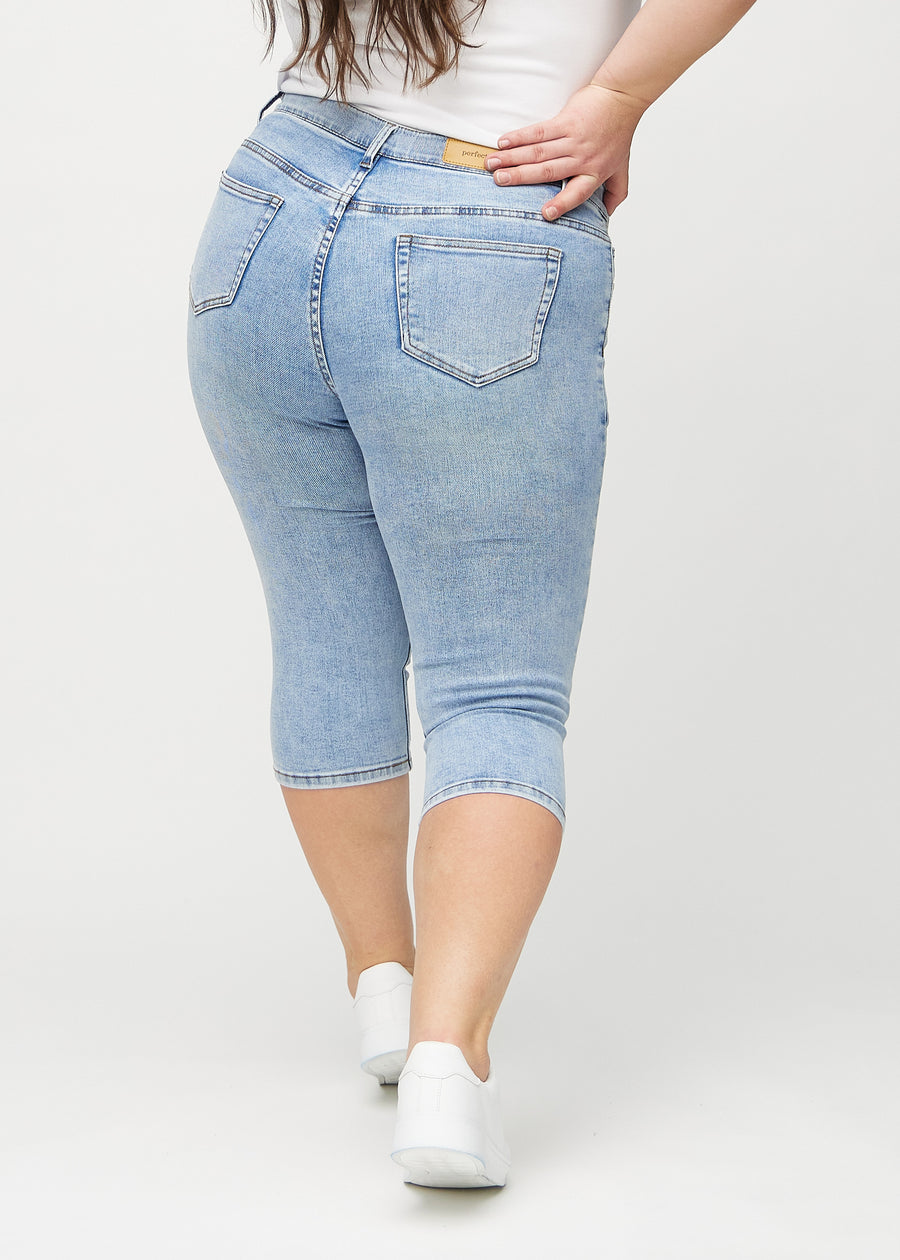 Skinny capris for women in light blue denim, color Waves. Back view on a plus-size model, showing the fit and back pockets.