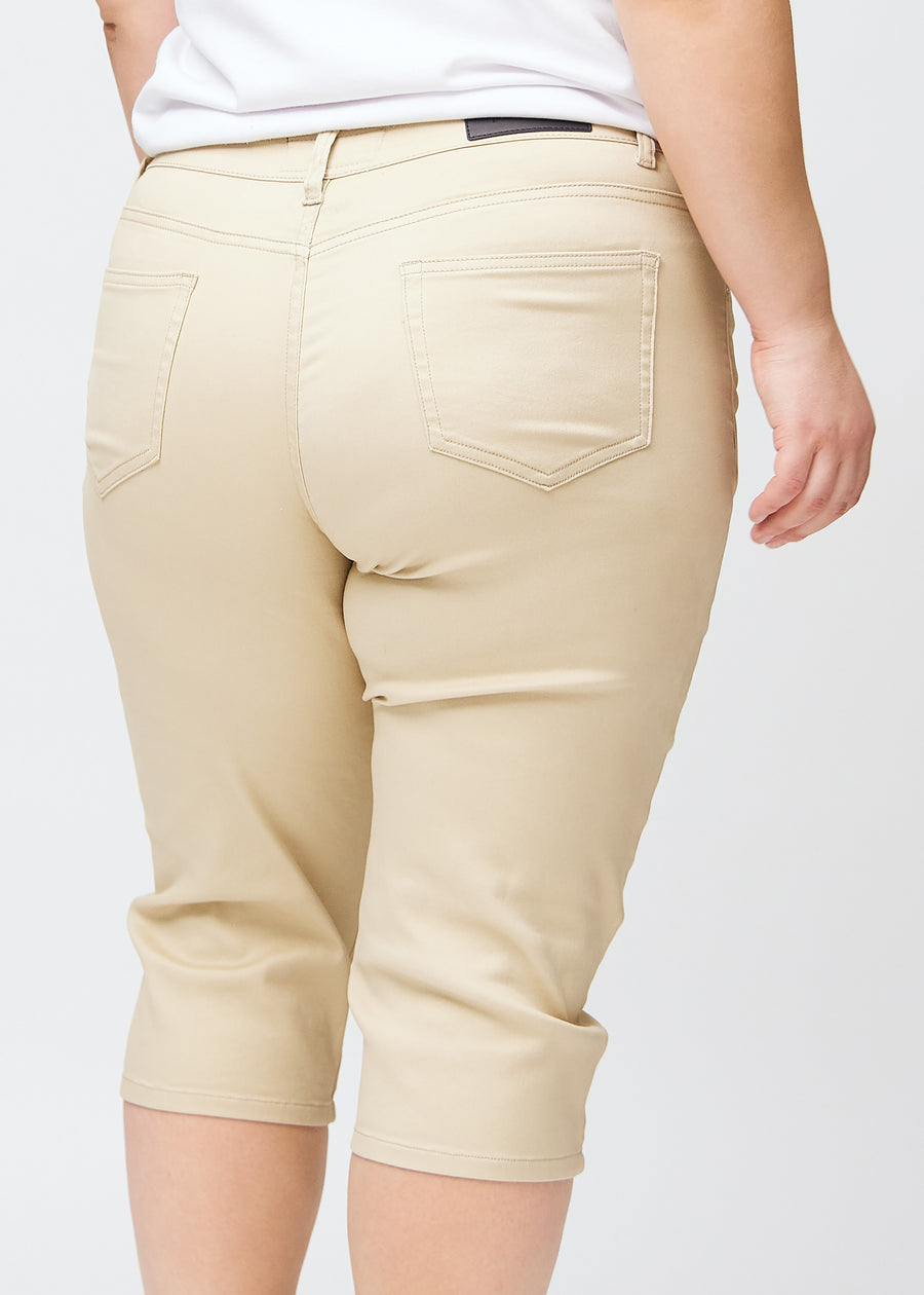 Slim capris for women in beige jeans fabric, color Gazelles. Close-up from behind on a plus-size model, highlighting the back pockets and stitching.