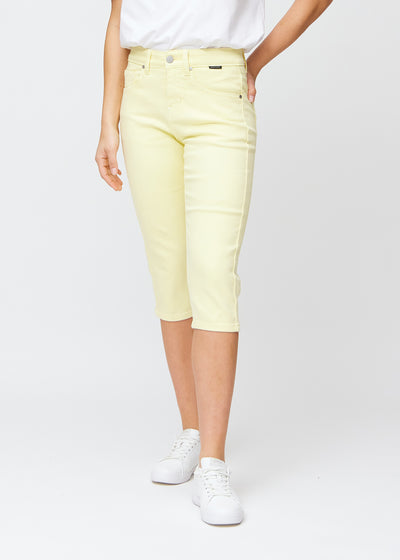Slim capris for women in pastel light yellow jeans fabric, color Lemonades. Front view on a model, showing the fitted cut ending just below the knee.
