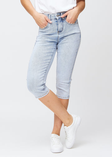 Slim capris for women in light blue denim, color Waves. Front view on a model, showing the fitted cut ending just below the knee.