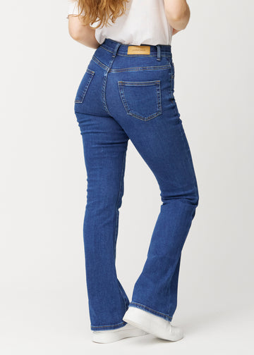 Dark blue mid-rise bootcut jeans in Oceans. Back view on a model, showing the full fit.