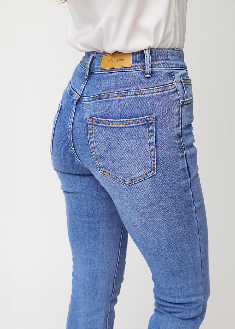 Blue mid-rise bootcut jeans in Rivers. Close-up back view on a model, showing the details.