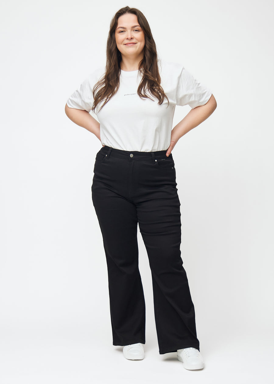 Full image of a plus-size model in black high-waisted bootcut jeans.