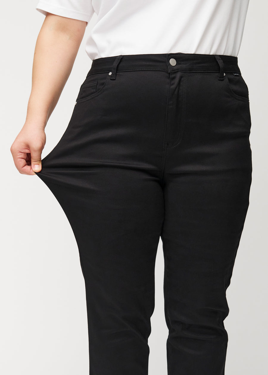 The plus-size model stretches the jeans at the thigh to show the stretch.