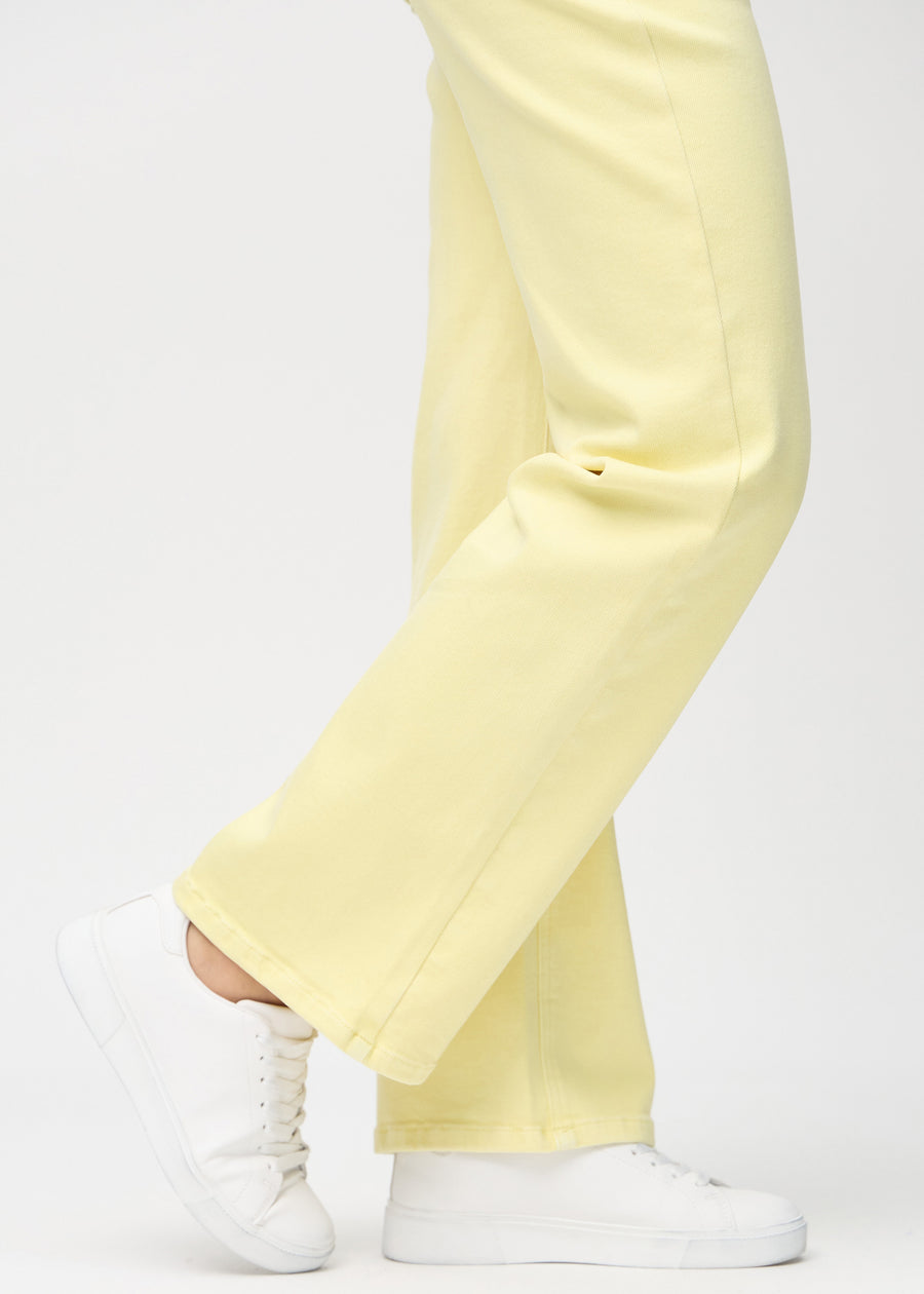 Loose jeans for women in light yellow, color Lemonades. Close-up at the ankles on a model, showing the wide leg openings.