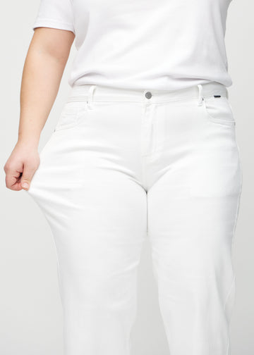 The plus-size model stretches the jeans at the thigh to show the stretch.