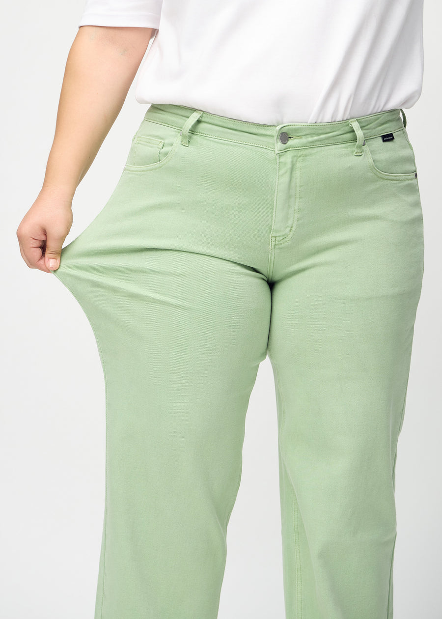 Loose jeans for women in light green, color Mints. A plus-size model stretches the denim at the thigh to show the fabric&