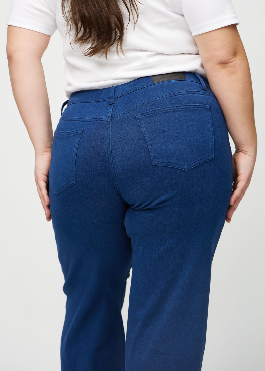 Dark blue loose jeans seen from the back close up on a plus-size model to show details.
