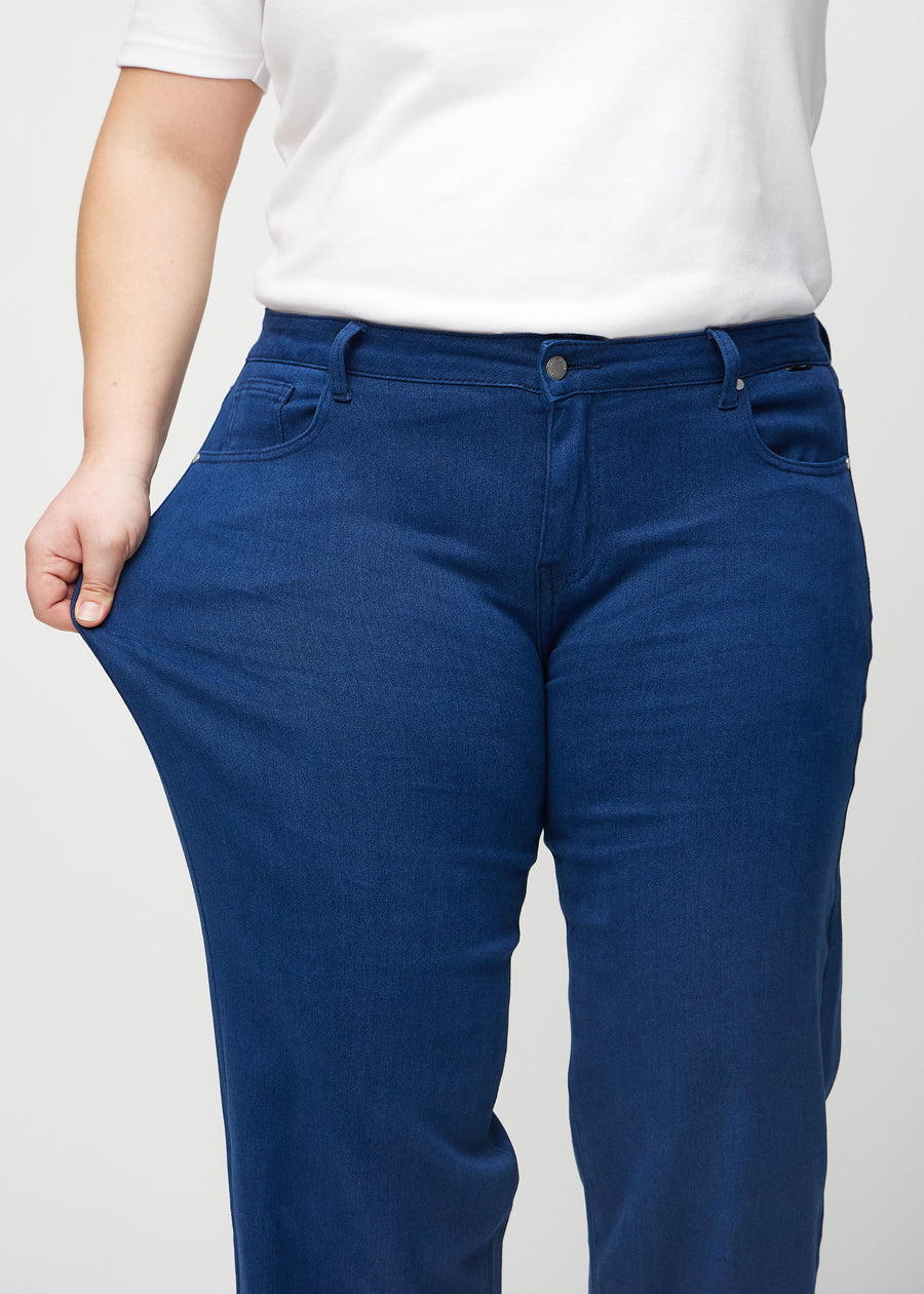 The plus-size model stretches the jeans at the thigh to show the stretch.