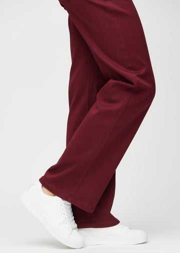 Loose jeans for women in dark red, color Santas. Close-up at the ankles on a model, showing the wide leg openings.