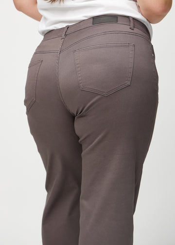 Grey-brown loose jeans seen from behind close up on a plus-size model to show details.