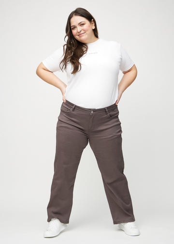 Full image of a plus-size model in grey-brown loose jeans.